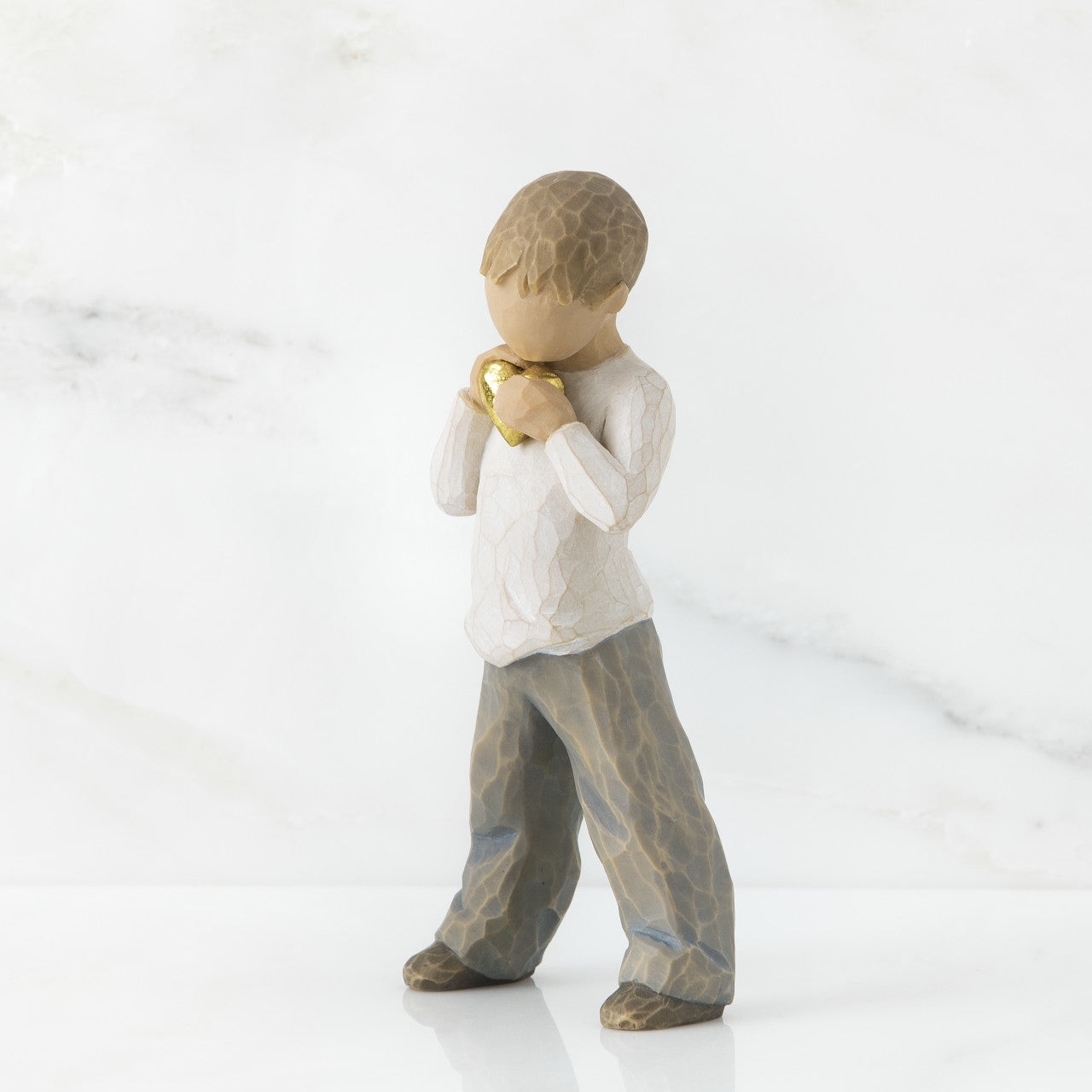 A young boy holding a golden heart close to their chest.
