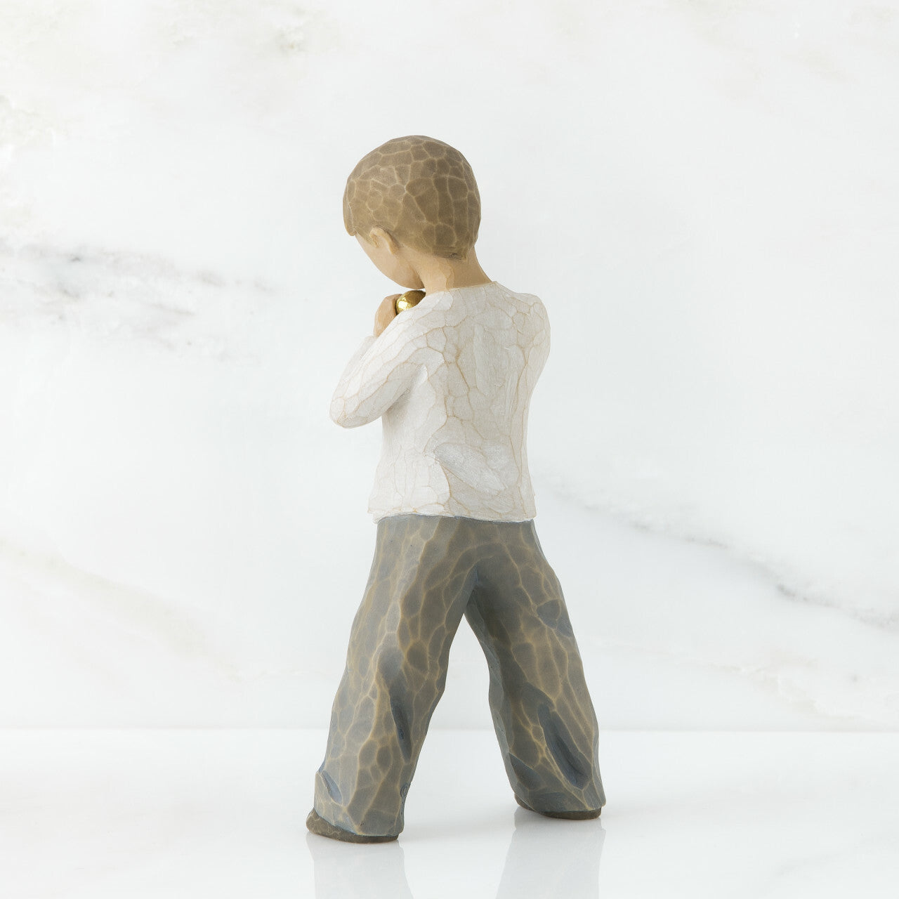 A young boy holding a golden heart close to their chest.