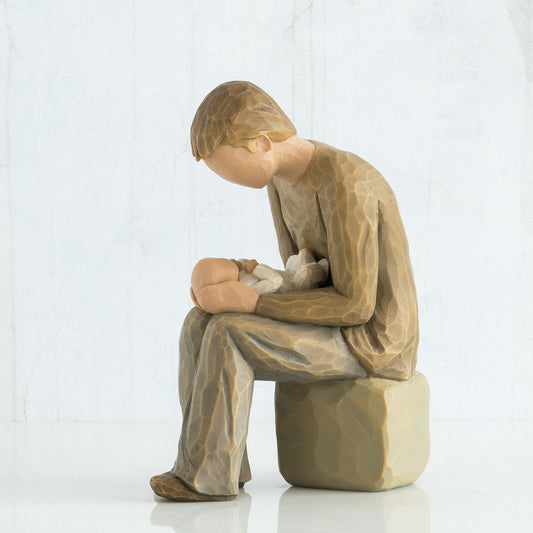 Willow Tree Figurine 'New Dad'. This figure depicts a man seated, holding a newborn baby in his lap, whilst looking down upon the baby.