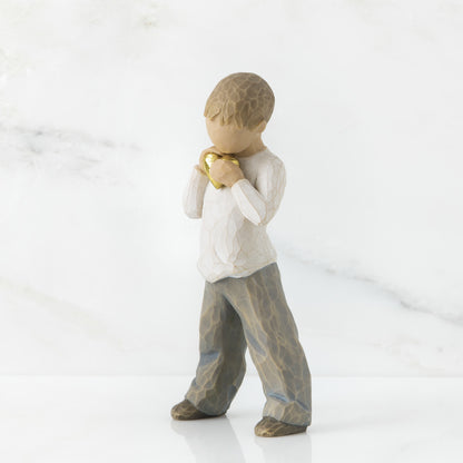A young boy holding a golden heart close to their chest.
