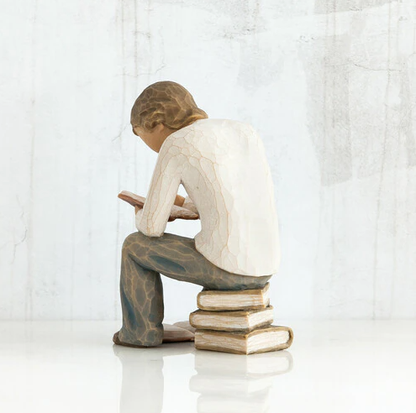 Willow Tree 'Quest' Figurine. A male figure seated on a stack of books with a book open at his feet, and another open in his hand as he leans over it reading.