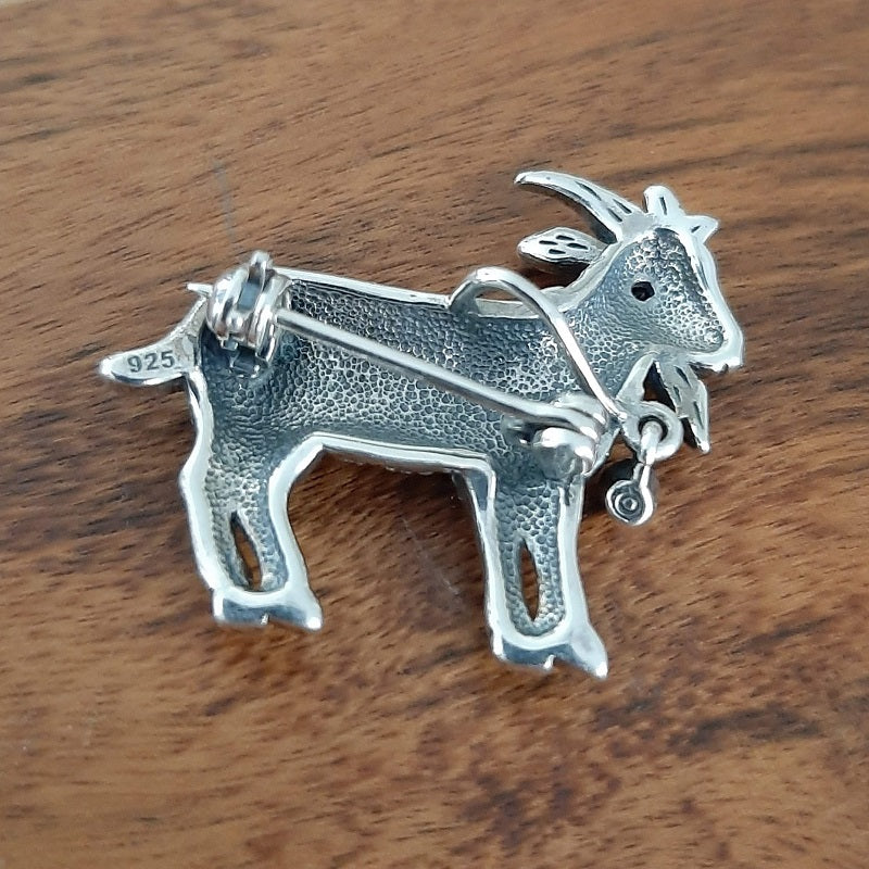 A sterling silver and marcasite goat with a red gem stone eye. The goat can be worn as a brooch, or as a pendant if. H 28mm W 32mm.